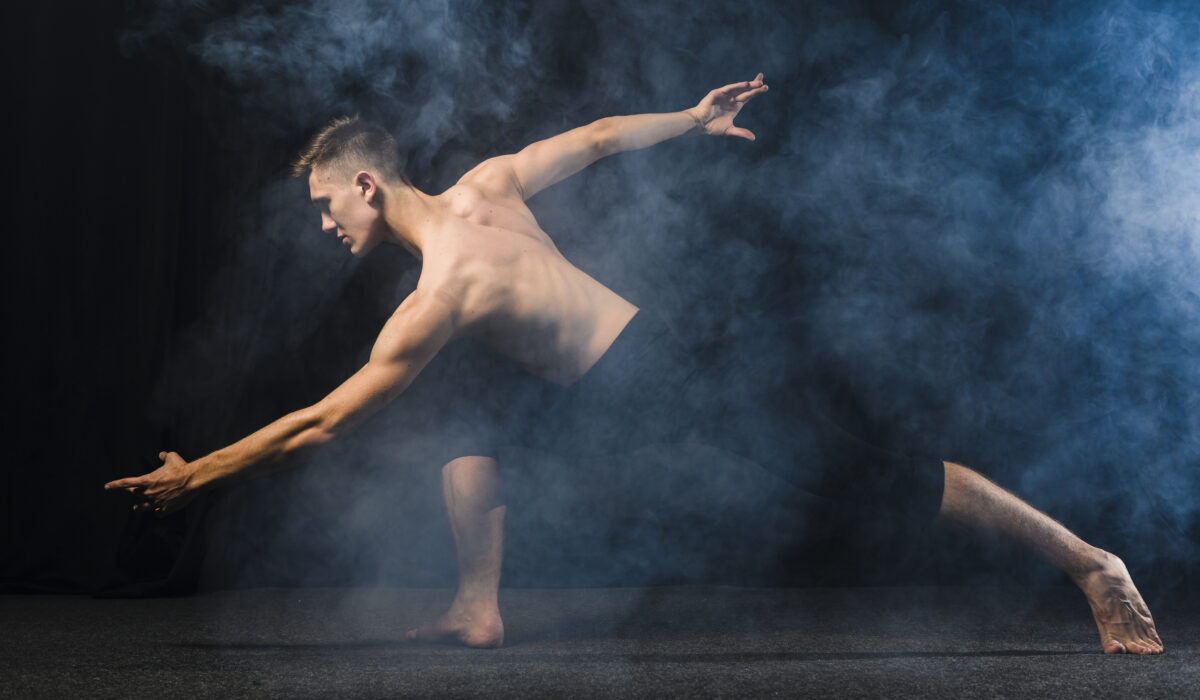 Jeune homme exerçant de la danse contemporaine , une léger voile de fumée recouvre la photo et le jeune homme ce trouve devant un font noir.