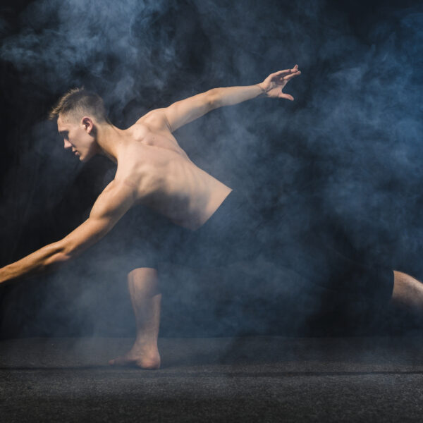 Jeune homme exerçant de la danse contemporaine , une léger voile de fumée recouvre la photo et le jeune homme ce trouve devant un font noir.